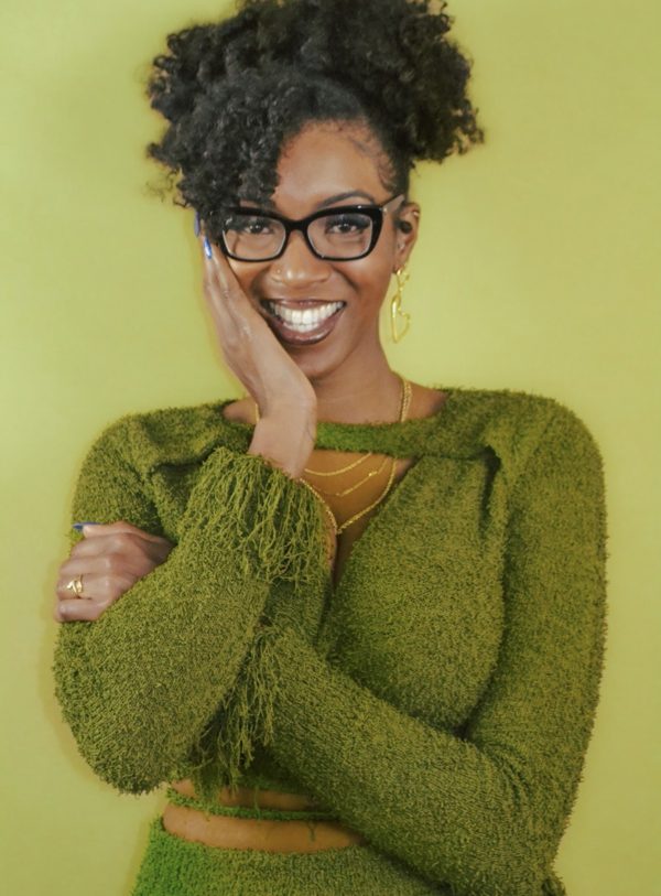Lauren A. Goodwin smiling in a green knit set against a chartreuse wall